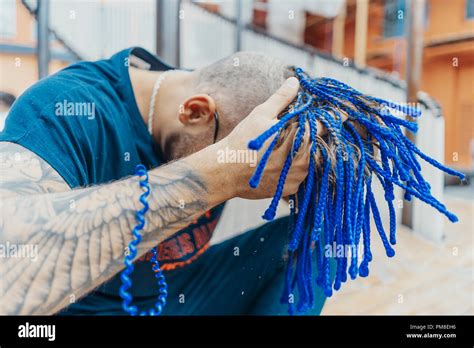 Young Attractive Man With Blue Dreadlocks Touching His Hair Stock Photo