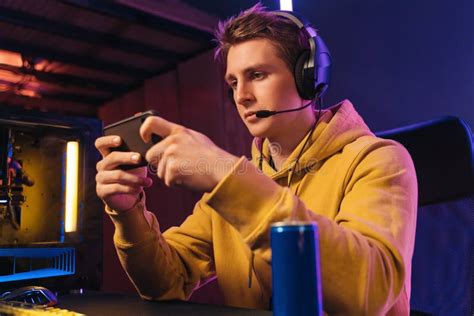 Young Pro Gamer Playing In Online Mobile Video Games In Neon Coloured
