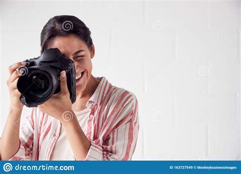 Female Photographer With Camera On Photo Shoot Against White Studio