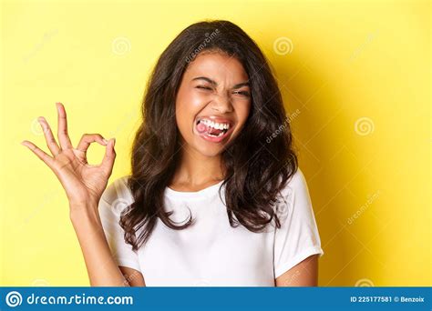 Close Up Of Cheerful African American Female Model Showing Okay Sign Winking And Looking