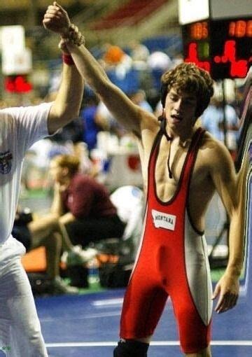 Two Men In Wrestling Uniforms Holding Their Hands Up To Each Other