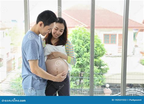Young Asian Husband Embracing And Touching Young Pregnant Belly Asian Wife With Love And Smile