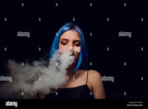 Young Woman Smoking Electronic Cigarette Against A Black Background
