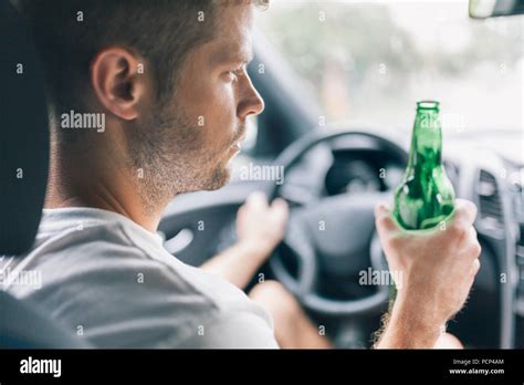 Drunk Driver Drinking Behind The Steering Wheel Of A Car Stock Photo