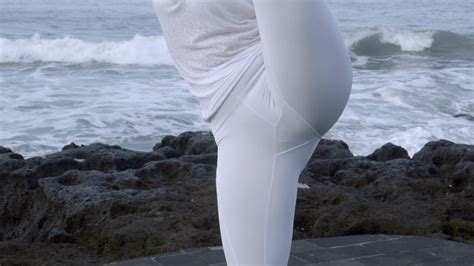 Tilt up of mature flexible woman in white doing bird of paradise yoga ...
