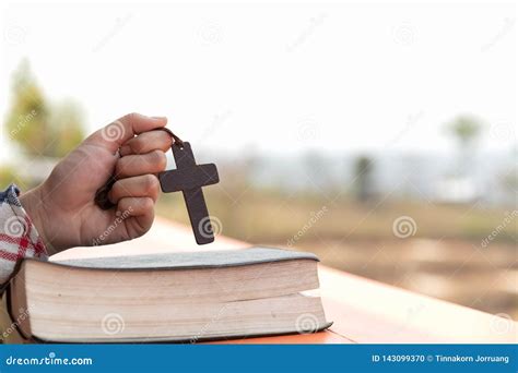 Close Up Young Hands Holding Wooden Cross Over Holy Bible And Praying
