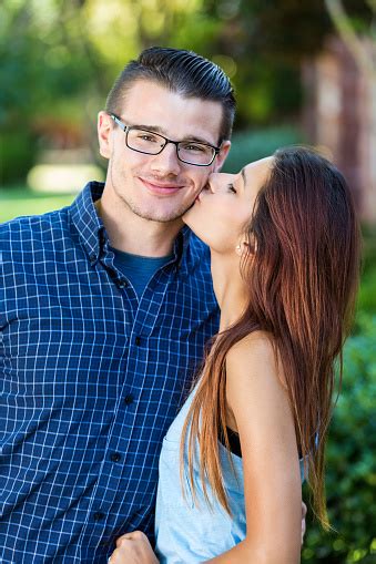 Young Woman Kissing Boyfriend On Cheek While Standing Outdoors Stock