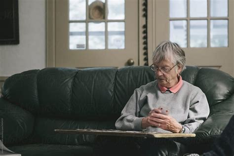 Senior Woman Relaxing At Home By Playing Solitaire Card Game Del