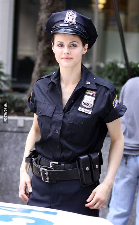 a woman police officer is walking down the street with her hands in her pockets and looking at