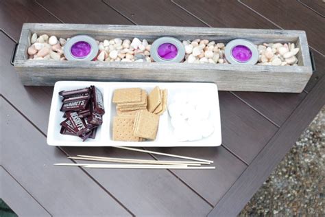 By making this cool diy s'more bar! DIY Tabletop S'mores Roasting Station - A Cup Full of Sass