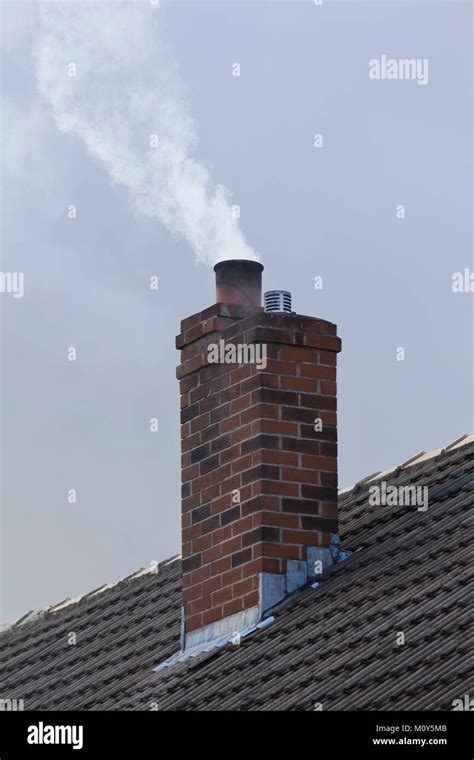 Chimney Stack On Domestic House With White Smoke Billowing From The