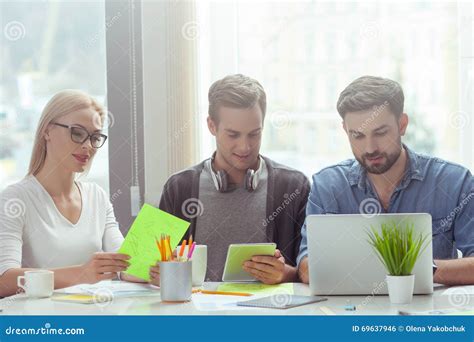 Cheerful Young Colleagues Are Working In Cooperation Stock Photo