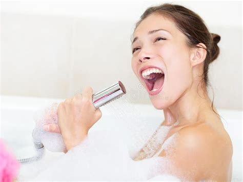 a woman in the bathtub with her mouth open while holding a shower head and smiling