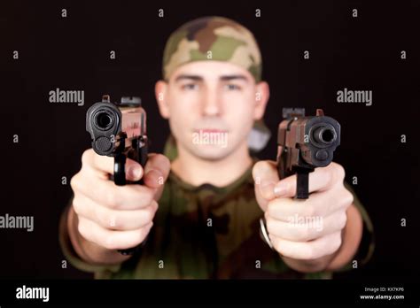 Modern Young Soldier With Two Guns Pointed At The Camera Stock Photo