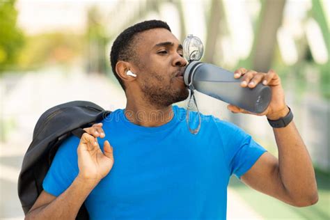 African American Young Sportsman Drinking Water Listening To Music And