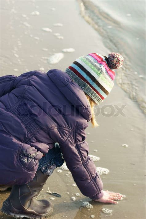 Efterår pige på stranden med hånd i vandet Stock foto Colourbox