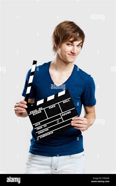 Casual Young Man Holding A Clapboard Over A Gray Background Stock