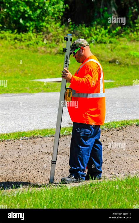 Highway Maintenance Worker Using A Digital Depth Guage As The Backhoe