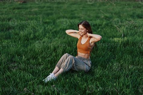 Une Jeune Rousse Femme Est Assis Sur Le Vert Herbe Dans Le Parc Avec Sa Bras Tendu Dans