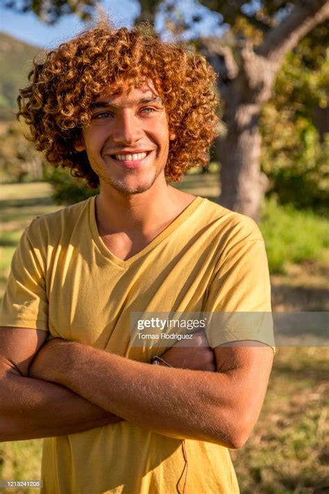 Portrait Of Smiling Young Man With Curly Red Hair In The Countryside