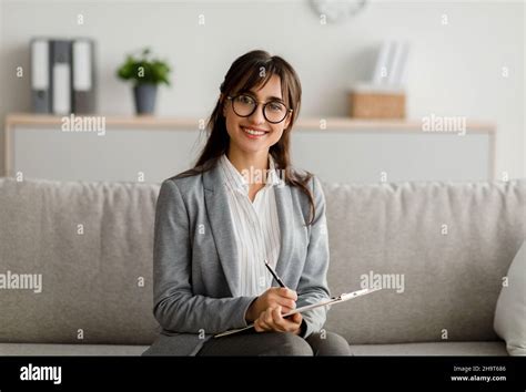 professional therapist concept portrait of female arab psychologist sitting on couch holding