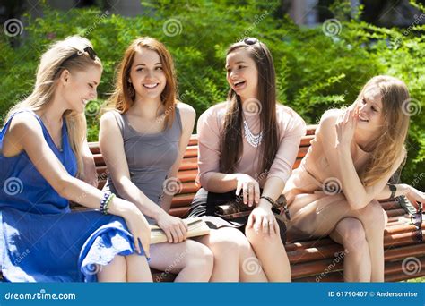 Vier Jugendlichen Die Auf Bank In Sommer Park Sitzen Stockbild Bild