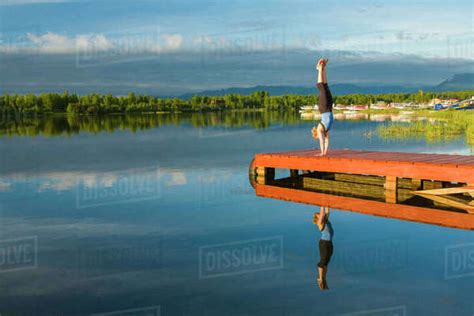 Caucasian Woman Practicing Yoga On Dock On Still Lake Anchorage