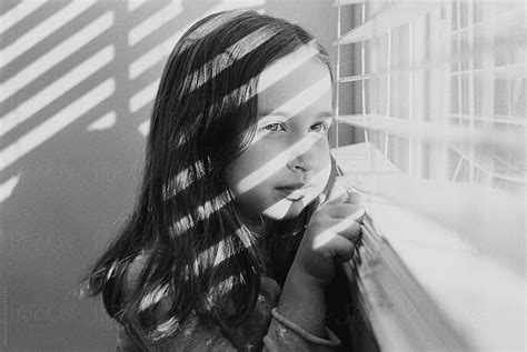 Black And White Portrait Of A Beautiful Young Girl Looking Out A Window By Stocksy Contributor