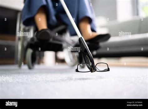 Disabled Woman In Wheelchair Using Grabber Tool Or Reacher For Fallen