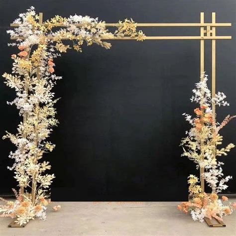 An Arch Made Out Of Branches And Flowers On The Side Of A Black Wall