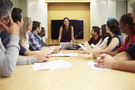 Female Boss Addressing Meeting Around Boardroom Table Stock Photo By
