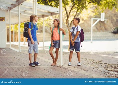 School Kids Talking To Each Other In School Corridor Stock Photo