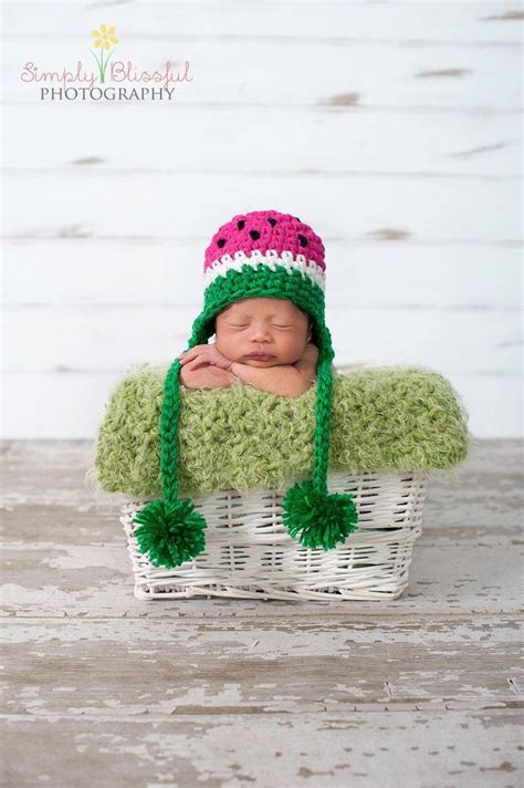 A Newborn Baby Wearing A Watermelon Hat In A Basket