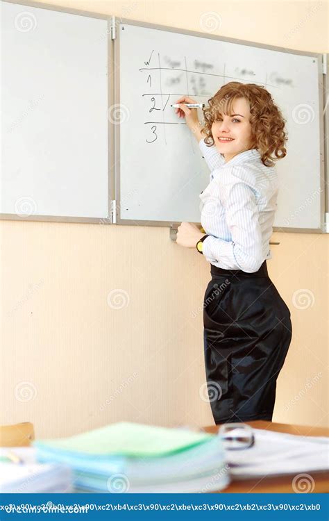 Teacher Stands At The Blackboard And Writing In The Classroom Stock