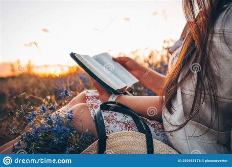 christian woman holds bible in her hands reading the holy bible in a field during beautiful