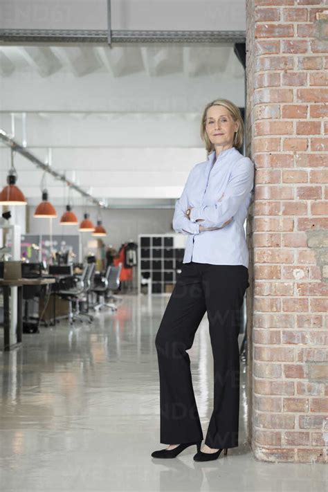 Mature Businesswoman Leaning Against Brick Wall Stock Photo