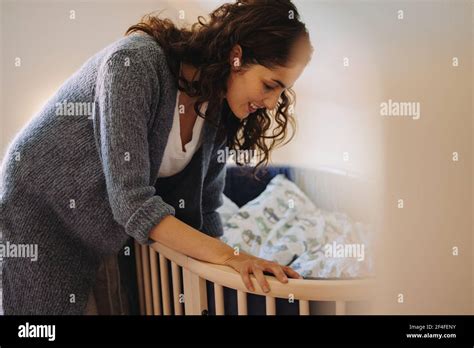 Loving Woman Putting Her Baby To Sleep In Crib Mother Looking After A