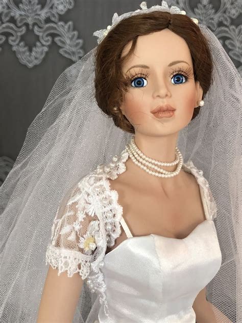 A Doll Wearing A Wedding Dress And Veil With Pearls On Its Head Is Shown