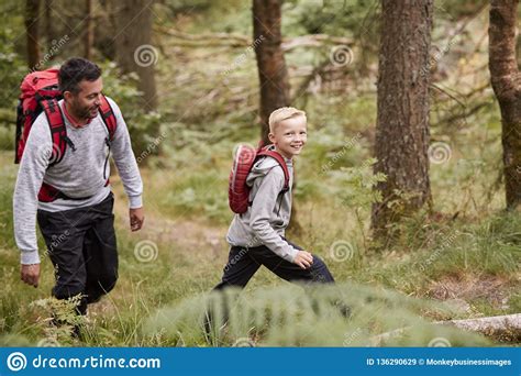 Side View Of A Boy Walking On Trail In A Forest With His