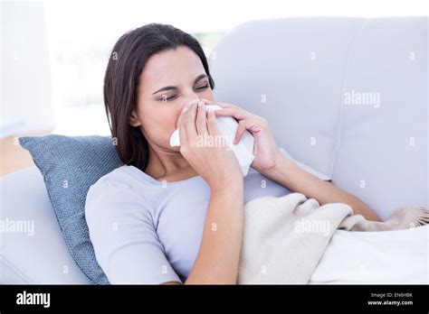 Sick Brunette Lying On The Couch And Blowing Her Nose Stock Photo Alamy