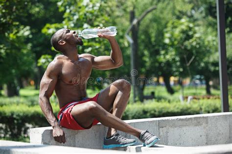 Athlete Resting And Drinking Water After Exercises At Stadium Stock