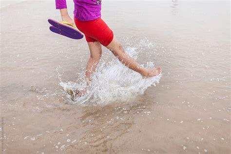 teenage girl splashing water by foot in a sea beach by stocksy contributor dream lover stocksy