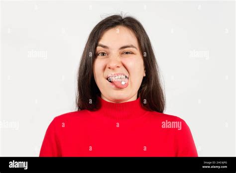 a woman in a red sweater with a white pill on her tongue with her mouth open writhes a