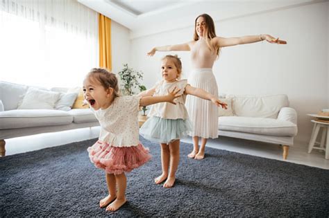 Mother Dancing With Preschool Daughters At Home Stock Photo Download