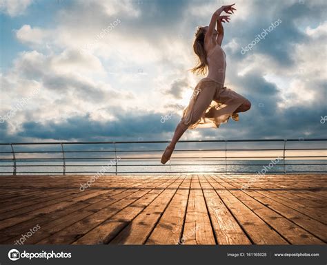 Jumping Ballerina In Beige Dress And Pointe On Embankment Above Ocean