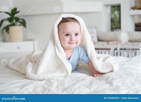 Cute Baby Boy 6 Months Old In Blu Bodysuit Smiling And Lying On Bed