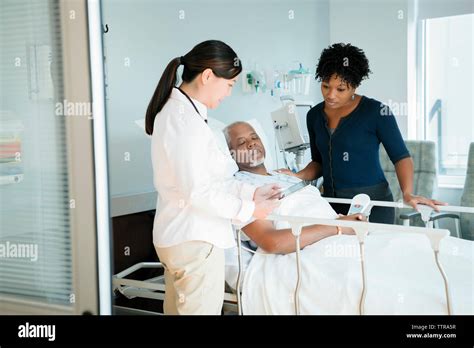 Female Doctor Showing Tablet Computer To Senior Patient And Woman In