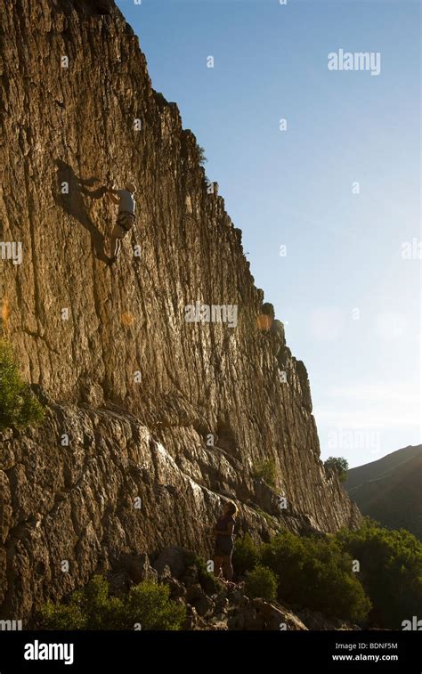 Male Rock Climber On A Sheer Cliff With A Strong Shadow Female Climber