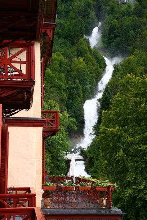 A View Of A Waterfall From The Top Of A Building With Red Balcony Railings