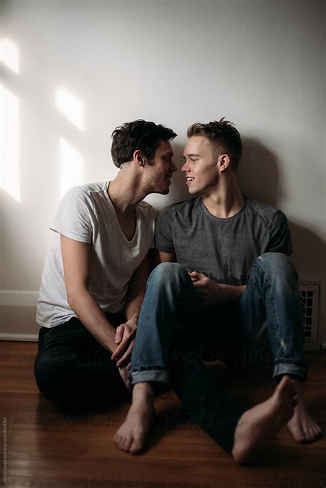 Young Gay Male Couple In Love Sitting On Bedroom Floor Del
